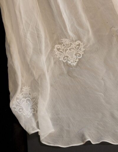 A sheer white fabric with two ornate white embroidered heart-shaped motifs near the edge.